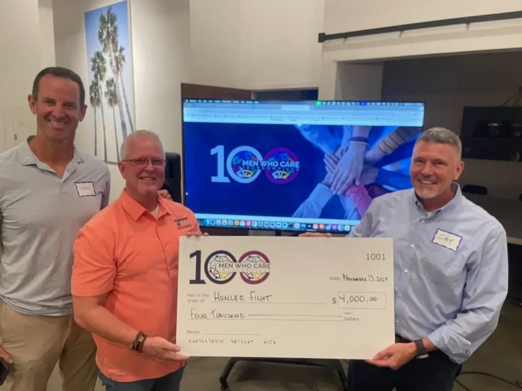 A check being awarded at an 100 Men Who Care Meeting